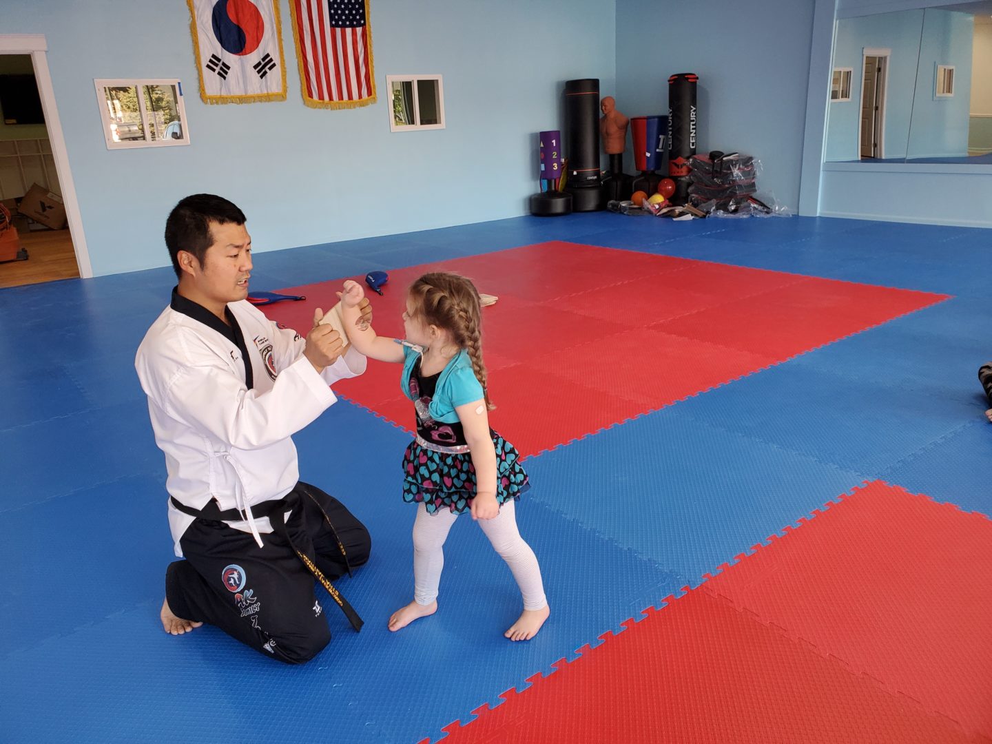Young student learning how to strike board from instructor Master Lee