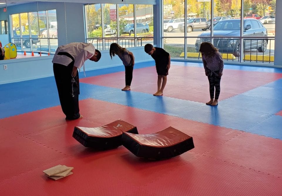 Three young students learning proper bowing technique from instructor